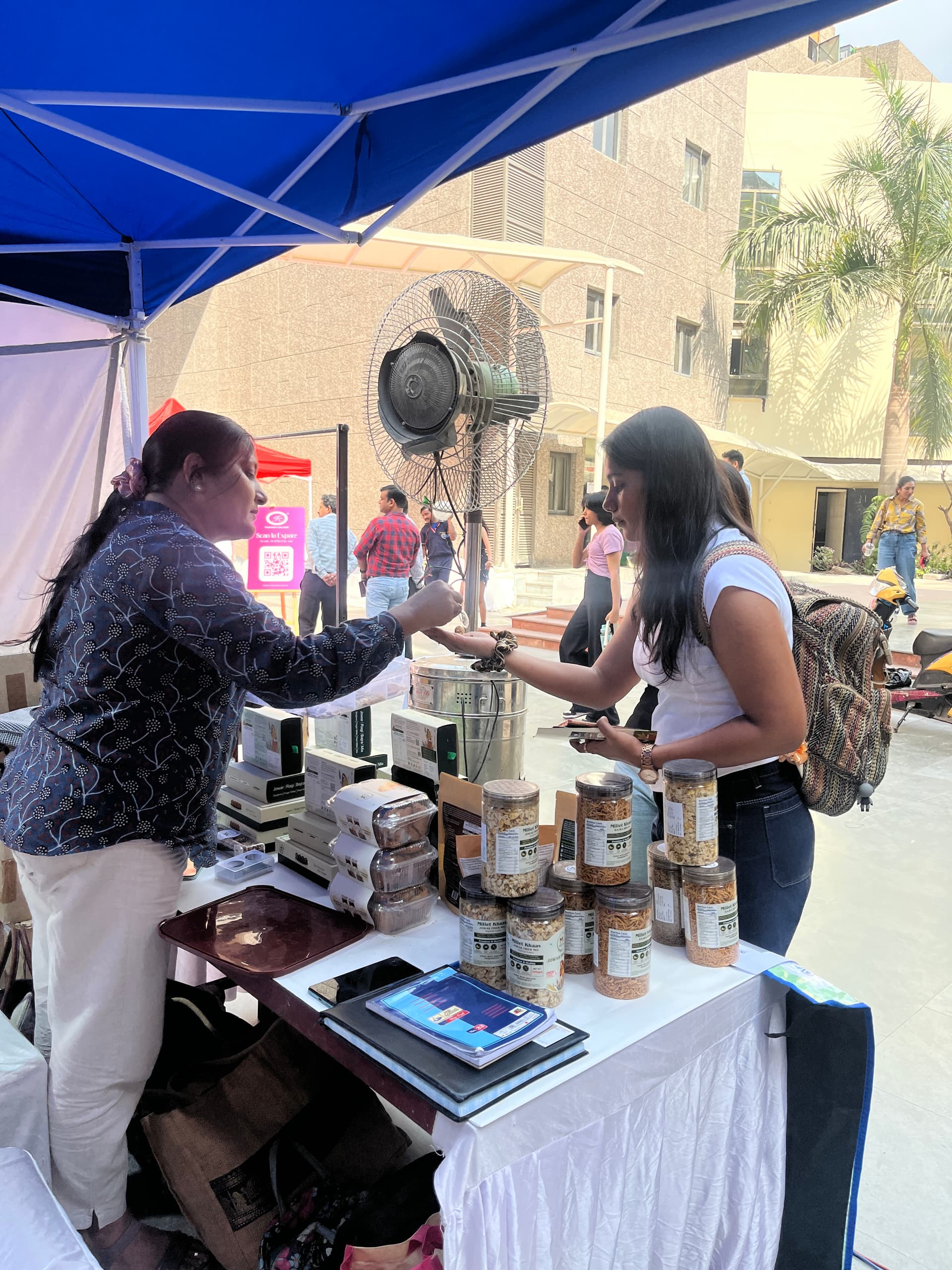 Millet Khaas at a college fest, handing a jar to a customer